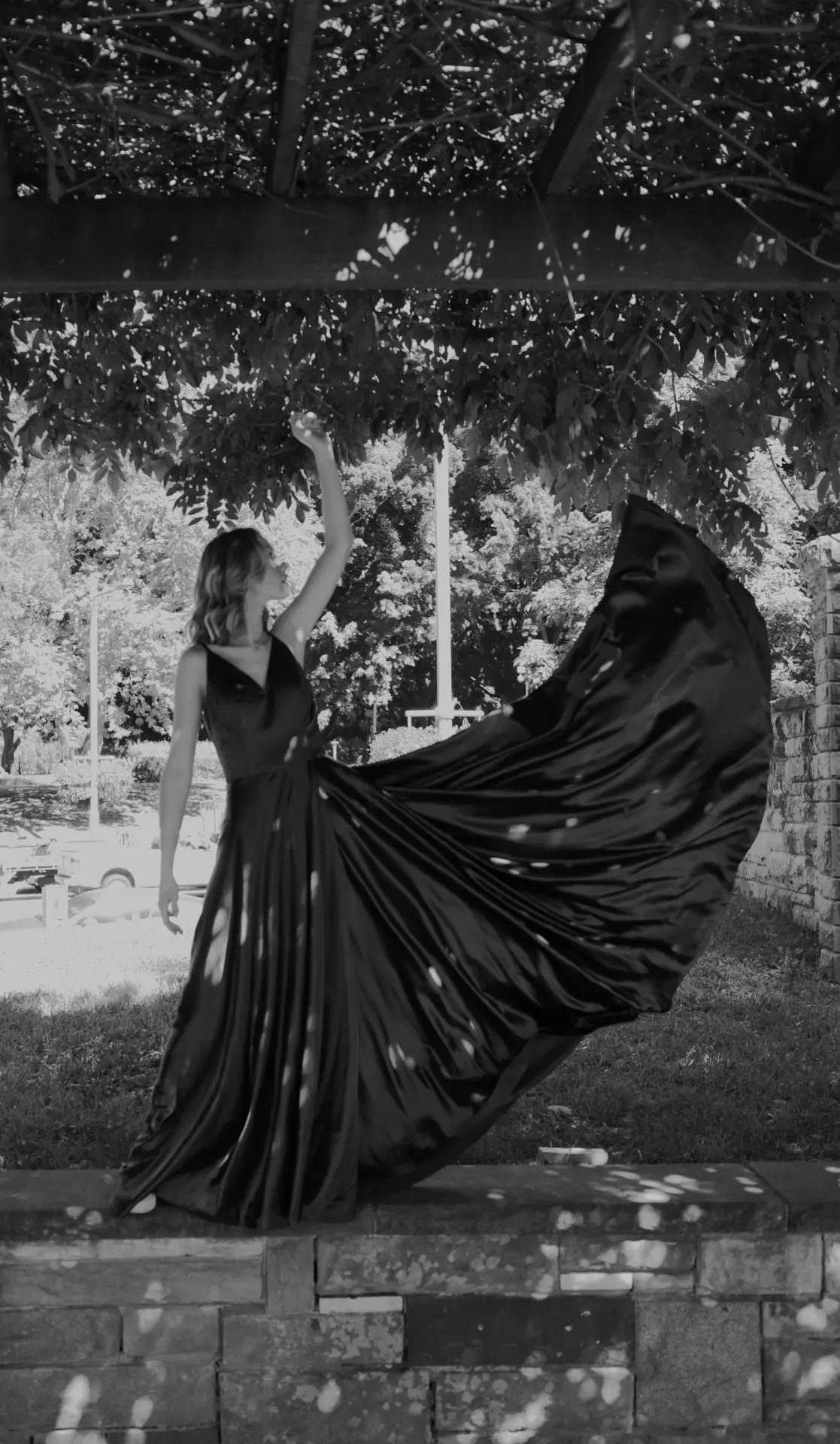 a woman in a long black dress standing under a tree